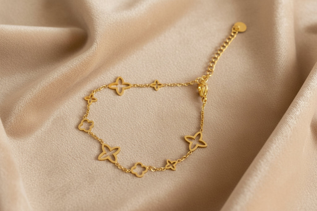 Ein Armband Gold mit verschiedenen Sternen liegt auf ein beigefarbenes samt tuch