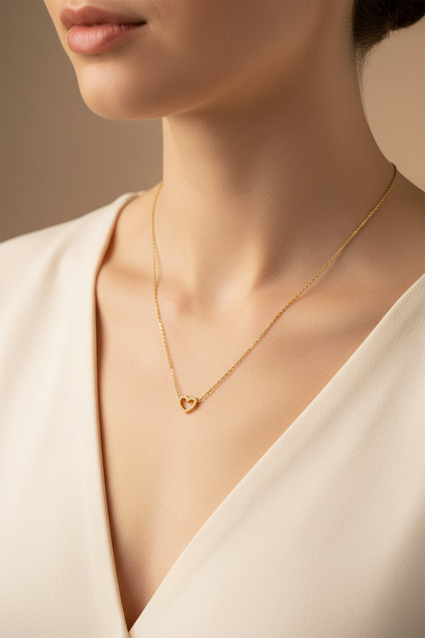 Eine Frau trägt eine goldene kette mit herzanhänger
