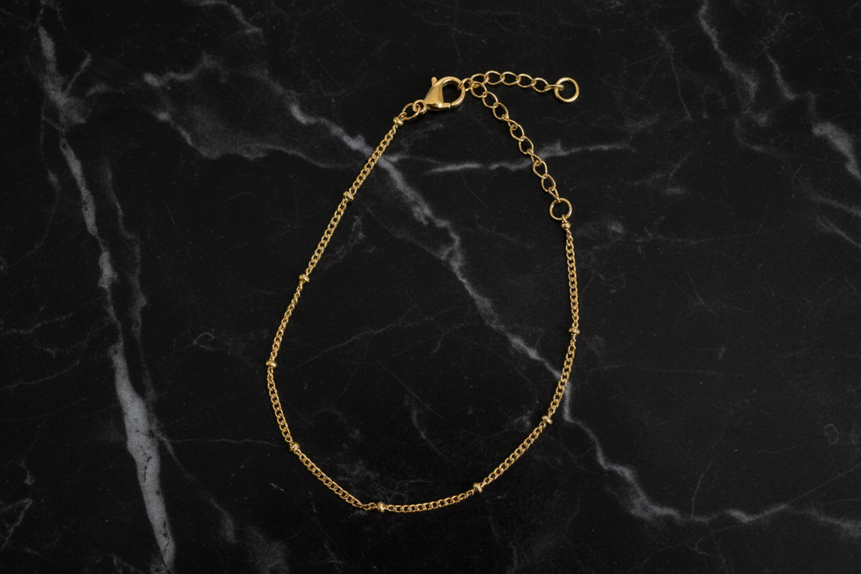 Armband mit filigranen Kügelchen liegt auf einer schwarzen Marmor platte
